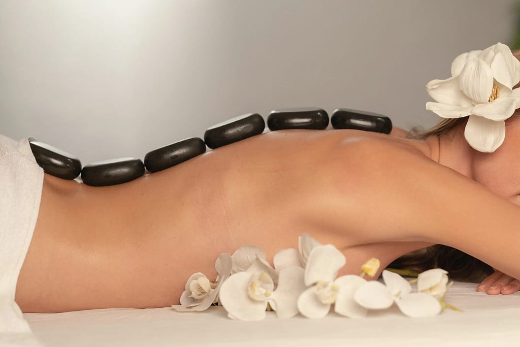 a person lying down with white flowers and black stones on her back